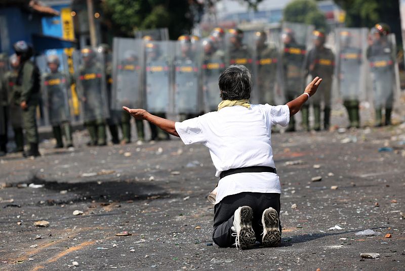 Un manifestante se arrodilla frente a las fuerzas de seguridad durante los disturbios en Udeña, Venezuela