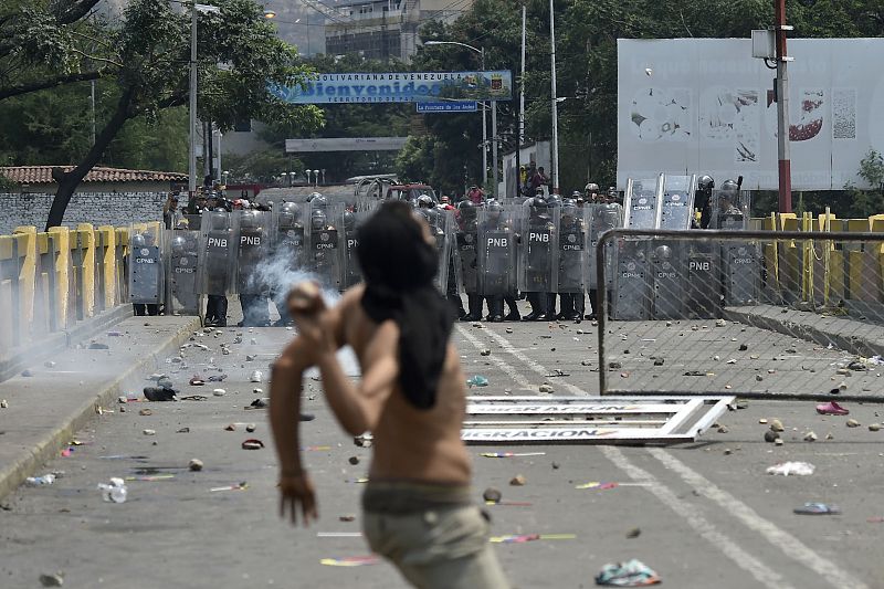 Un hombre se dispone a lanzar un objeto contra los agentes de seguridad del Gobierno de Maduro en el puente fronterizo de Simón Bolívar