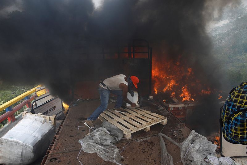 Un hombre descarga ayuda humanitaria de un camión que ha ardido en el puente fronterizo de Francisco de Paula Santander