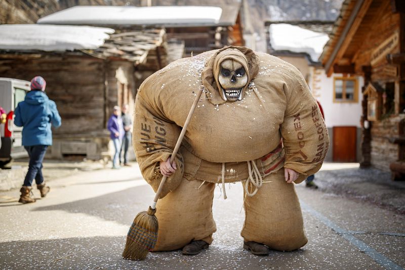 Un hombre vestido con el tradicional traje de hombre de paja y máscara del diablo participa en el desfile de carnaval de la villa alpina de Evolène