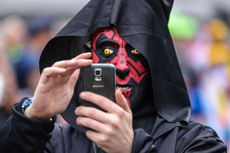 Una persona disfrazada toma una fotografía con su teléfono móvil durante la marcha de carnaval