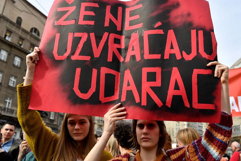 Un grupo de mujeres jóvenes sostienen un cartel que dice "Las mujeres contraatacan" durante un mitin que conmemora el Día Internacional de la Mujer en la capital serbia de Belgrado.