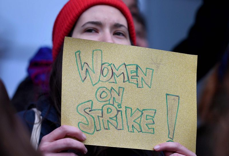 Una mujer sostiene un cartel que dice "Mujeres en huelga", mientras que las mujeres miembros del Parlamento Europeo realizan una la protesta en la entrada principal para conmemorar el Día Internacional de la Mujer en Bruselas.