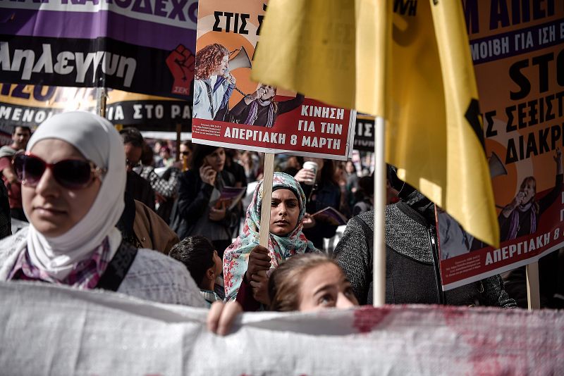 Las mujeres migrantes participan con pancartas en una marcha en el centro de Atenas durante una huelga para conmemorar el Día Internacional de la Mujer.