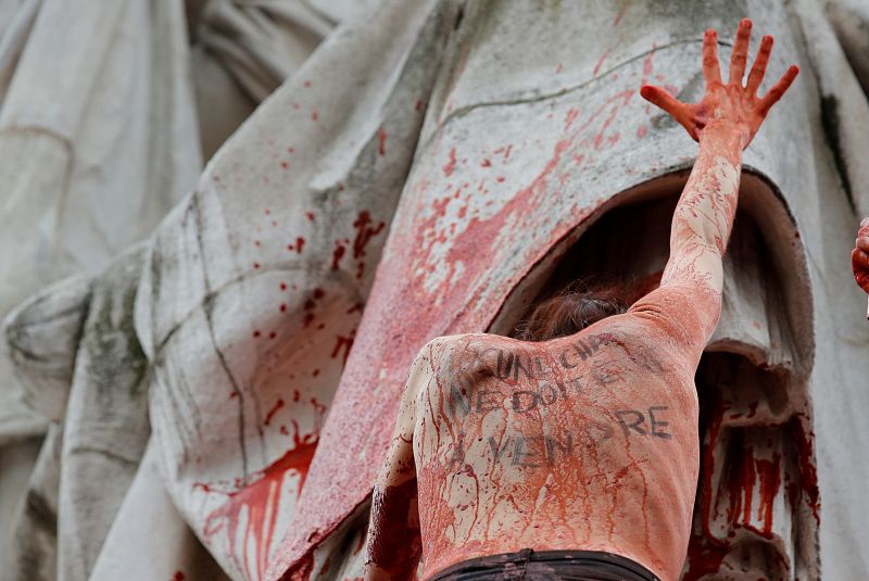 Una mujer con el mensaje escrito en su espalda, "No se debe vender carne", mientras se detiene en una estatua de la Plaza de la República durante la protesta para resaltar la disparidad salarial entre mujeres y hombres.