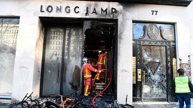 Dos bomberos trabajan en uno de los comercios arrasados en las protestas