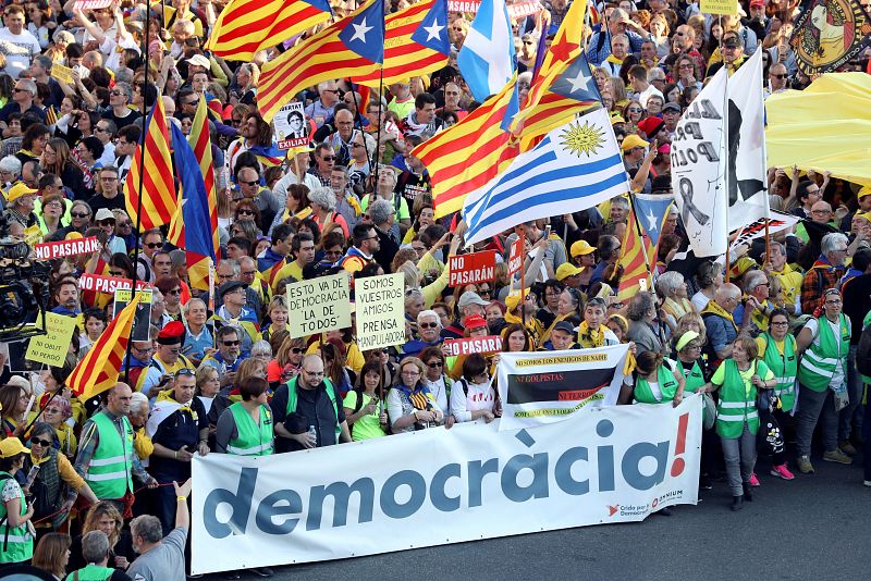 Asistentes a la manifestastación con una pancarta bajo el lema 'democracia'