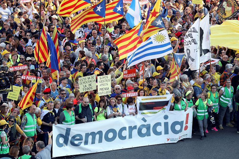 Asistentes a la manifestastación con una pancarta bajo el lema 'democracia'