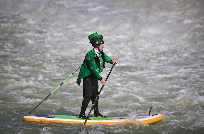 Un hombre vestido de verde rema sobre una tabla en el río Lech, en la ciudad alemana de Landsberg am Lech