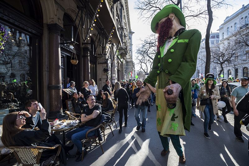 Los clientes de una cafetería de Budapest, Hungría, miran divertidos a un gigante durante la celebración de San Patricio