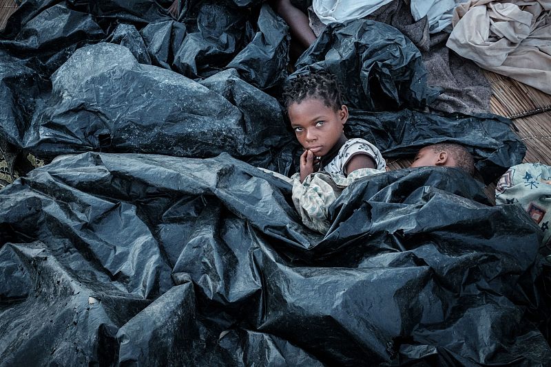 Enia Joaquin Luis, de once años, se despierta junto a su hermana Luisa, de 6, bajo unas mantas de plástico en Búzi, Mozambique