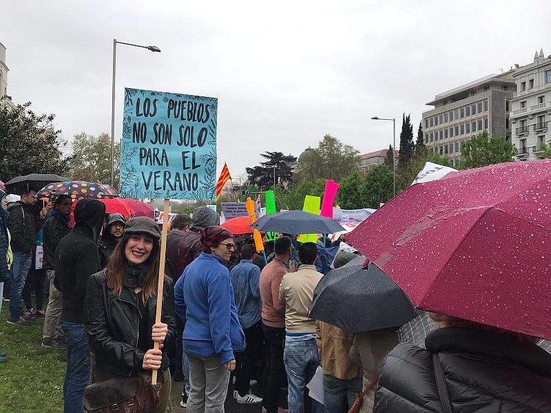 Una mujer con una pancarta en la que se lee "Los pueblos no son solo para el verano"