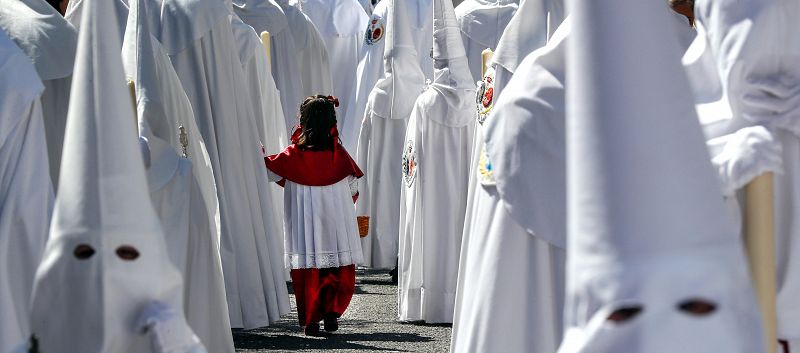 Una niña acompaña a los Nazarenos de la Paz en la estación de penitencia de su Hermandad