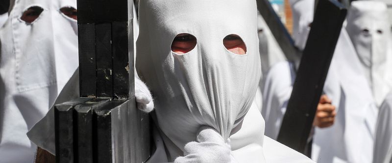 Penitentes de la Paz en la estación de penitencia de su Hermandad, en la jornada en la que comienzan los desfiles procesionales del Domingo de Ramos