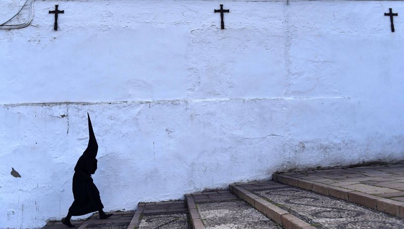 Un nazareno sube por la Cuesta del Bailío después de que la hermandad de los Dolores La Señora de Córdoba haya suspendido su paso de Viernes Santo por la amenaza de lluvias