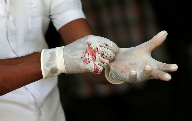 Un policía forense con los guantes ensangrentados en la morgue en Colombo