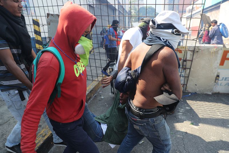 Simpatizantes de Guaidó ayudan a un herido durante una manifestación en apoyo a su levantamiento contra el gobierno de Nicolás Maduro este martes.