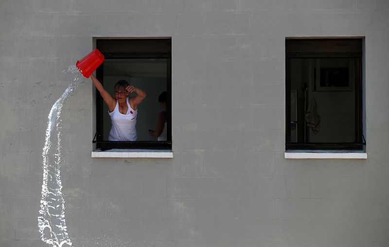 Una mujer arroja agua desde una ventana durante el chupinazo