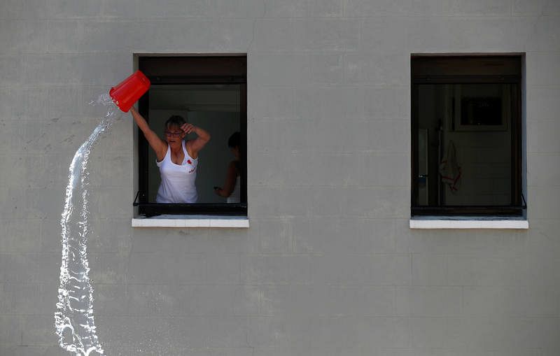 Una mujer arroja agua desde una ventana durante el chupinazo