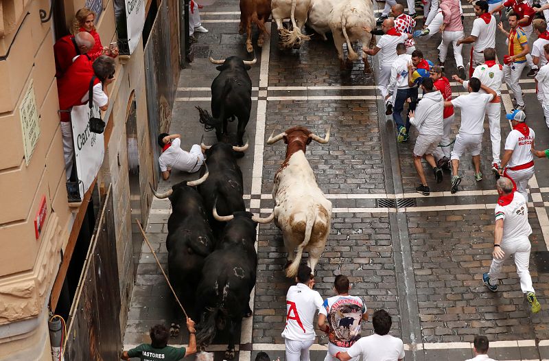 Un corredor cae delante de los toros durante el primer encierro de los Sanfermines 2019.