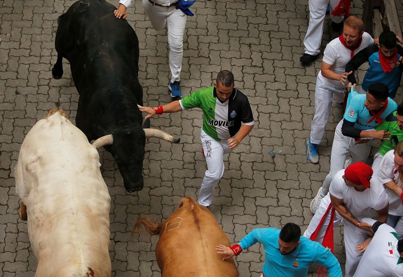 Uno de los corredores toca los toros de la ganadería de Puerto de San Lorenzo en el primer encierro de los Sanfermiens 2019. 