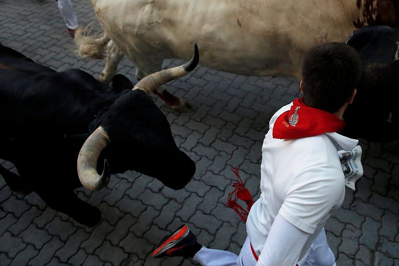Un corredor pasa muy cerca de los toros de la ganadería La Palmosilla durante el encierro.