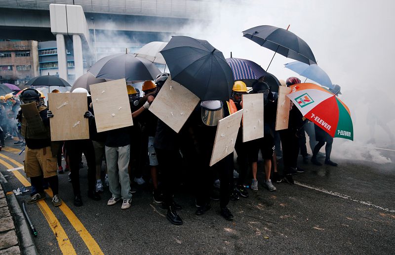 Los manifestantes usan escudos y paraguas para protegerse