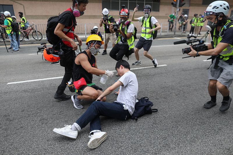 Un manifestante asiste a un compañero que sufre los efectos de los gases lacrimógenos lanzados por la policía