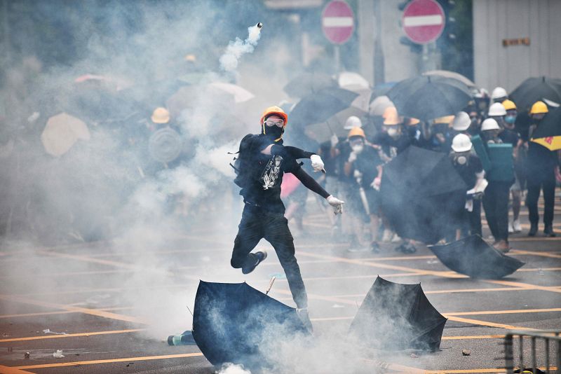 Un manifestante lanza de vuelta un bote de gas lacrimógeno a la policía