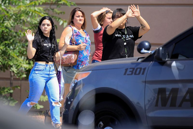 Clientes del centro comercial Walmart salen con las manos en alto tras el tiroteo. 