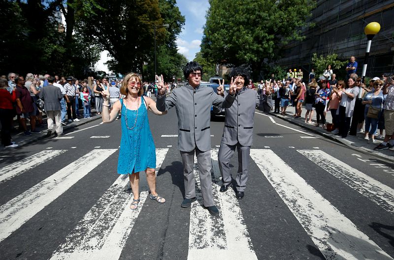 Fans de The Beatles posan en el centro del paso de cebra de Abbey Road.