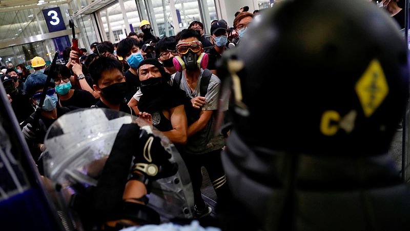 Manifestantes contra la ley de extradición se enfrentan a ala policía en el aeropuerto de Hong Kong