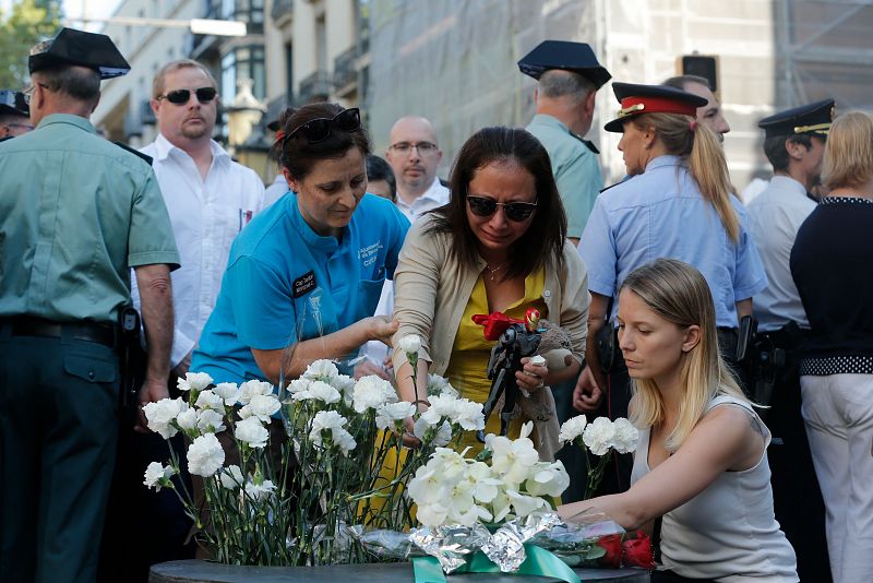 La madre de una de las víctimas deposita claveles blancos en el Memorial