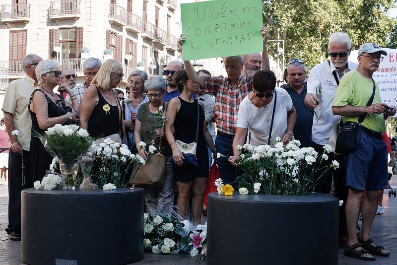 Un hombre muestra una pancarta en la que se lee "Queremos saber la verdad" durante los actos de homenaje a las víctimas.