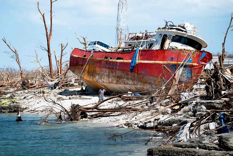 Habitantes de Bahamas recuperan objetos de una embarcación encallada en la playa.