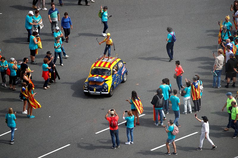 Un grupo de personas observa un coche pintado con la estelada antes del inicio de la manifestación independentista con motivo de la Diada