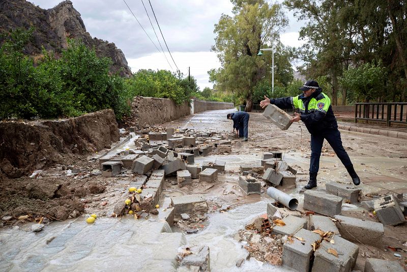 Gota fría: Policías locales retirando los bloques de un muro derribado por las fuertes lluvias caídas en el barrio de Runes en Blanca, Murcia.