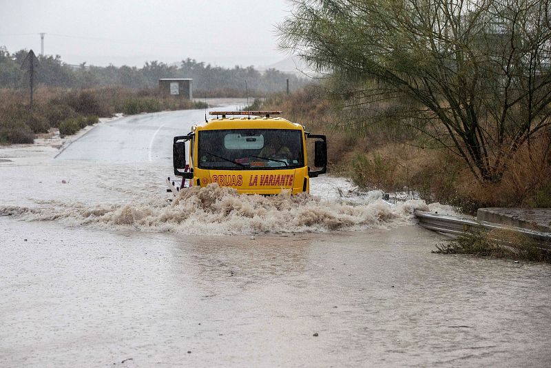 Gota fría: Una grúa pasando por la rambla de la Cañada Morcillo, en el polígono industrial de La Estrella en Molina de Segura, durante un momento de intensa lluvia.