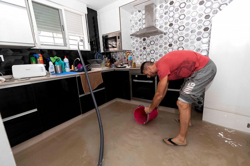 Gota fría: Un hombre recogiendo agua con un cubo en la cocina de su vivienda en Blanca, Murcia.