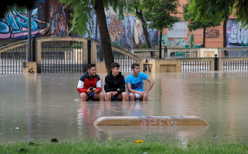 Gota fría: Unos jóvenes contemplan la inundación sentados en un banco en un parque de Orihuela, cerca del río Segura,