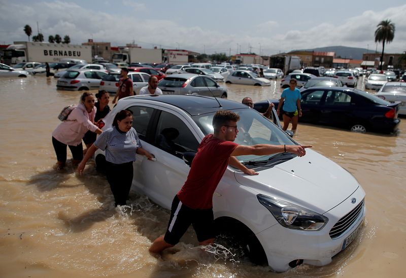 Gota fría: Un grupo de personas empuja un coche en un parque inundado en Orihuela, Alicante. 