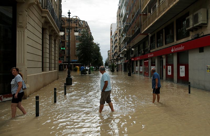 Habitantes de Orihuela caminan por las calles inundadas de la ciudad.