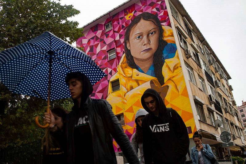 Un grupo de jóvenes camina frente a un mural que representa a Greta Thunberg en el distrito Kadikoy de Estambul