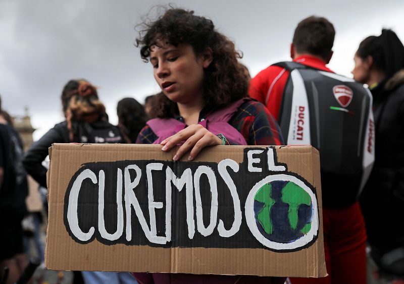 Una mujer sostiene una pancarta en la que se lee "Curemos el mundo"