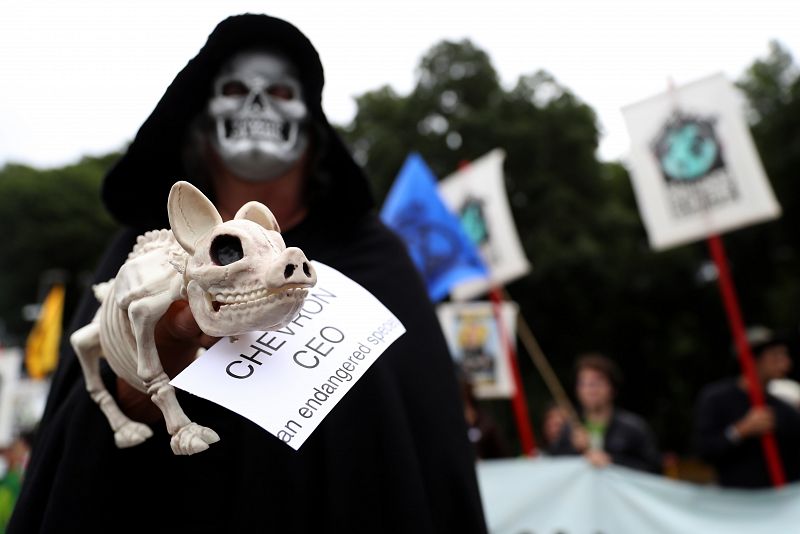 Un activista sostiene el esqueleto de un perro de juguete con un cartel en el que se lee: "Consejero delegado de Chevron", en la marcha que ha tenido lugar en la localidad californiana de San Ramon