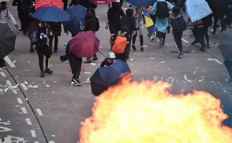 Un manifestante se protege con su paraguas mientras se producen las violentas protestas en las calles de Hong Kong.