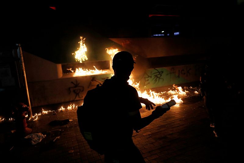 Un manifestante antigubernamental se para frente a un incendio cerca de la estación Sham Shui Po, durante una manifestación en el Día Nacional de China en Hong Kong,