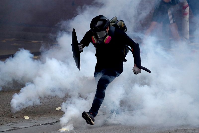 Un manifestante antigubernamental atraviesa una nube de gas lacrimógeno durante una protesta en el distrito de Sham Shui Po, en el Día Nacional de China en Hong Kong,