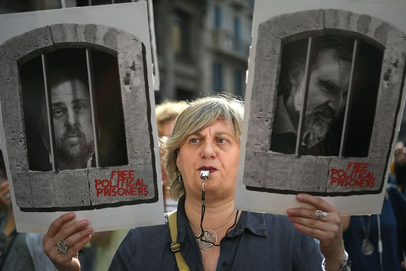 Una manifestante porta las fotografías de los líderes independentistas Oriol Junqueras y Jordi Cuixart, en Barcelona.