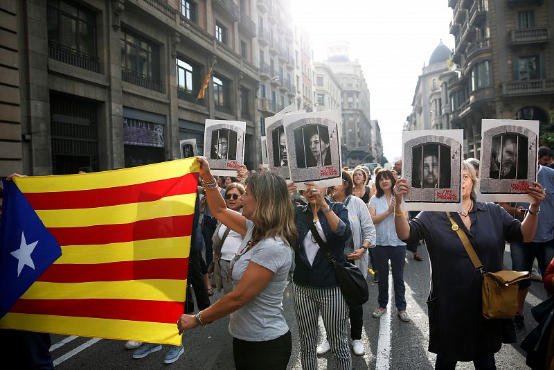 Manifestantes portan una estelada y fotografías de los líderes independentistas, en la Vía Laetana de Barcelona.